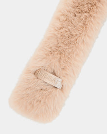 Close-up of the CARMY - L425534 Vanilla, a soft, light beige women’s faux-fur scarf by Rudsak, featuring a rectangular leather patch embossed with the brand name—offering plush warmth and stylish cold-weather comfort.