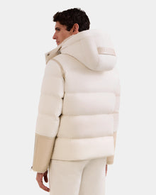 A person is seen from the back, looking to the side against a white background, wearing the Rudsak DAVID - M125508 Vanilla puffy lamb shearling hooded winter jacket with beige sleeves and white pants.