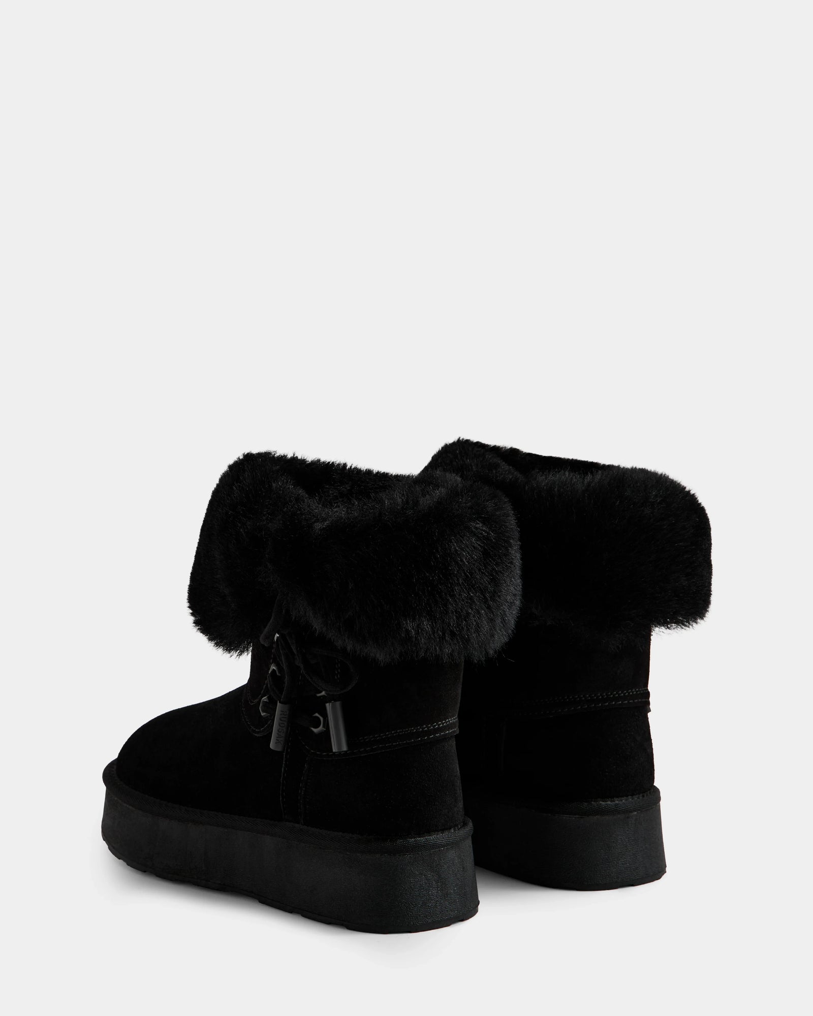 The Rudsak INESA - L225026 Black women's suede platform boots feature thick faux fur cuffs, flat soles, cozy wool lining, and decorative side bows. Shown on a white background.