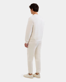A person faces away from the camera, dressed in Rudsak's MAXTON - U525007 Vanilla M cotton-blend joggers, a matching long-sleeve top, and white sneakers, all set against a plain light background.