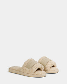 A pair of vanilla, open-toe women’s slippers—TEDDY - L225517 by Rudsak—with fuzzy faux-shearling, a wide band across the top, flat soles, and a cozy, plush look. Perfect for loungewear.