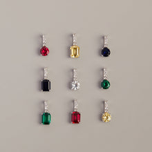 Model. Set of earrings with colored gemstones on a gray background