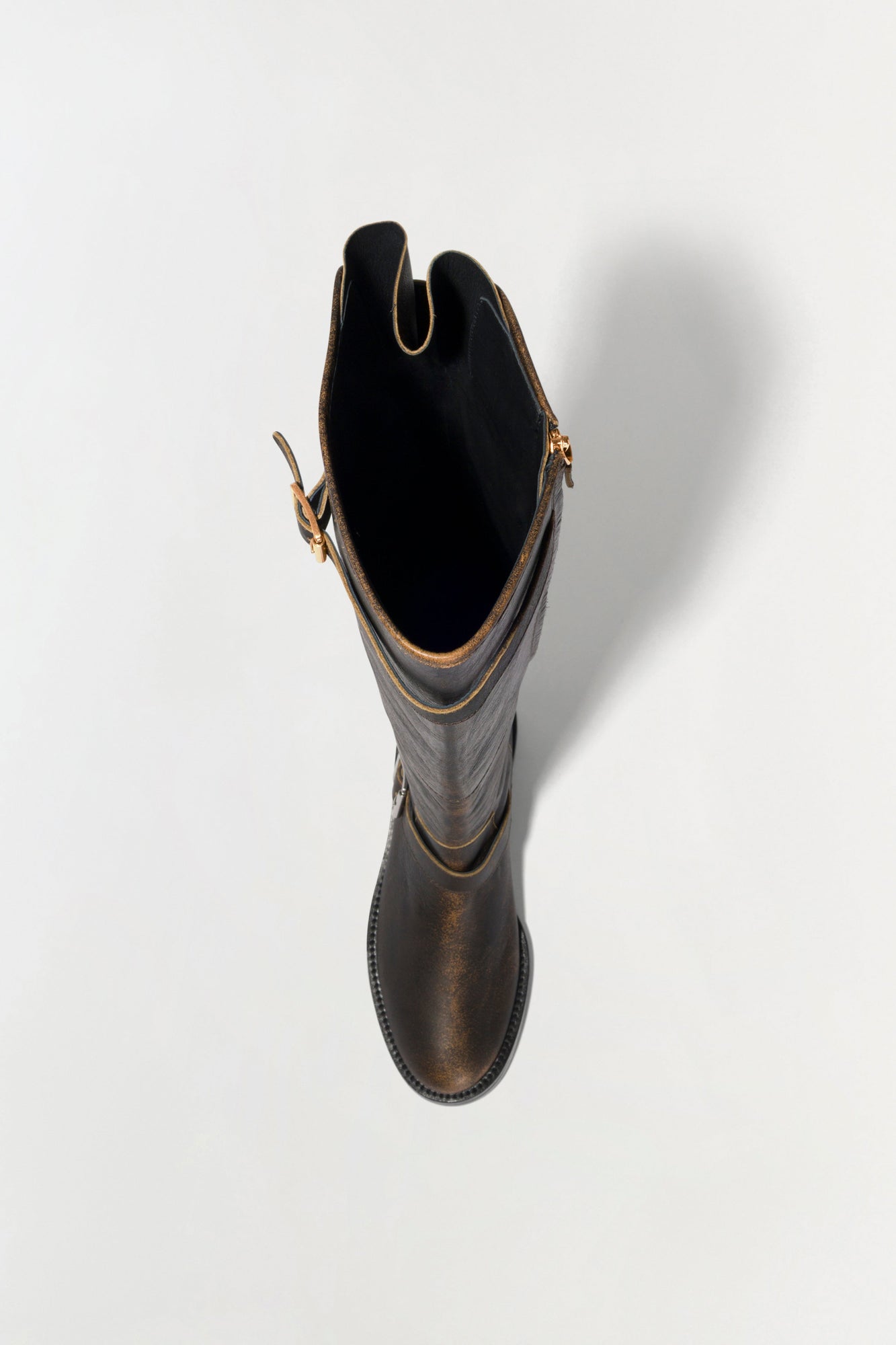 Black leather over-the-knee boot with gold-tone hardware and buckle details, shown from above against a white background.