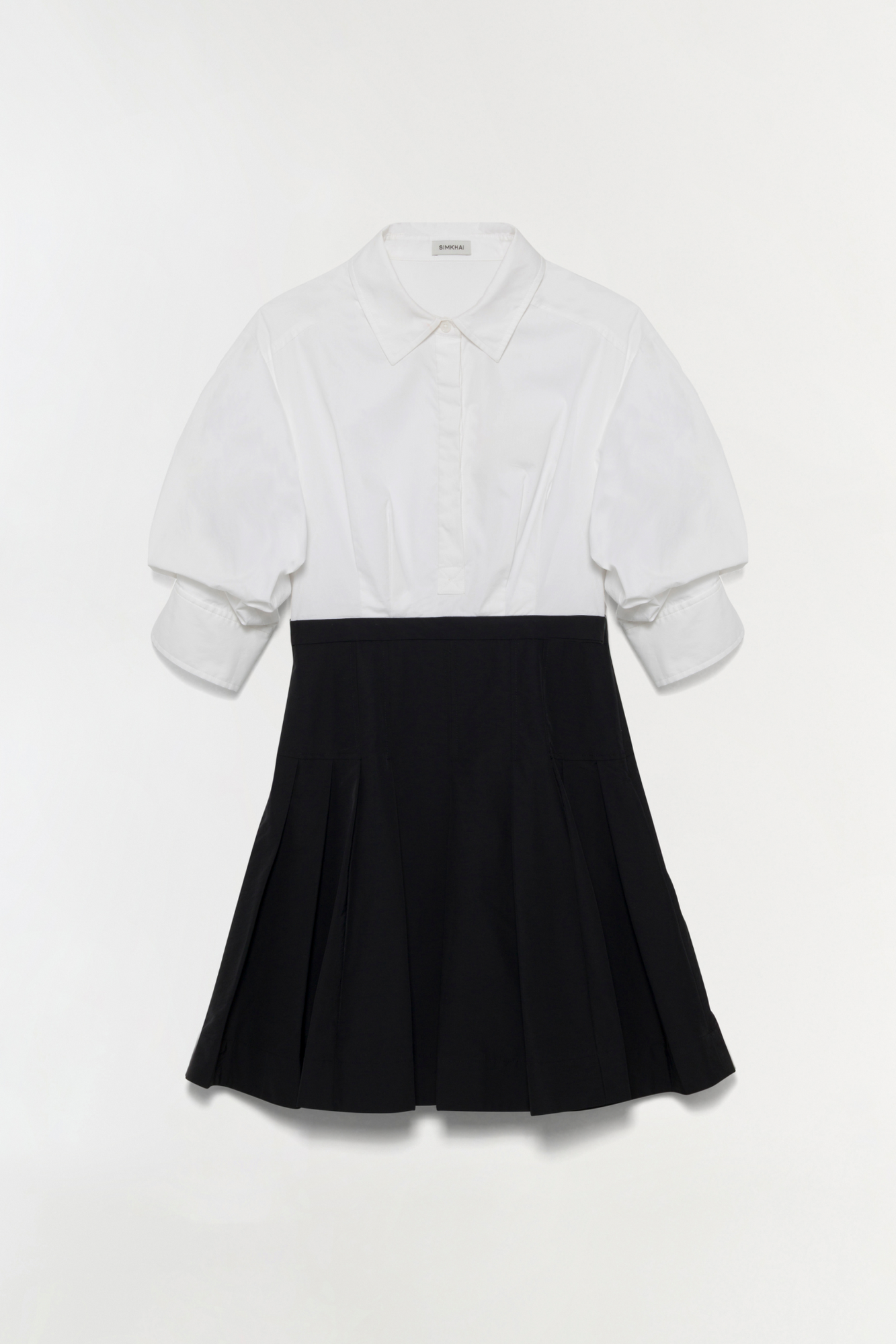 White cotton shirt dress with black pleated skirt and collar detail.