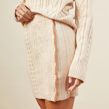 Close up view of model wearing the sweater mini skirt in off white.