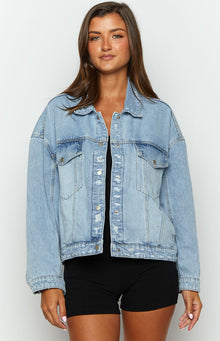 Front view of a light wash oversized denim jacket with distressed button placket and chest pockets