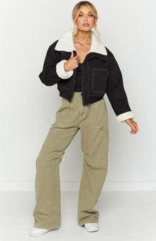 Close-up of a black denim sherpa jacket with white sherpa collar and cuffs, featuring white contrast stitching and silver zip