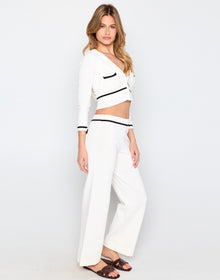 Woman wearing a white outfit with black accents on a plain background