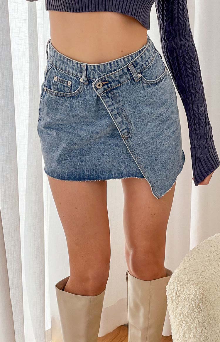 Beginning Boutique Jendi Denim Mini Skirt light blue denim mini skirt with an asymmetrical wrap front and raw hem