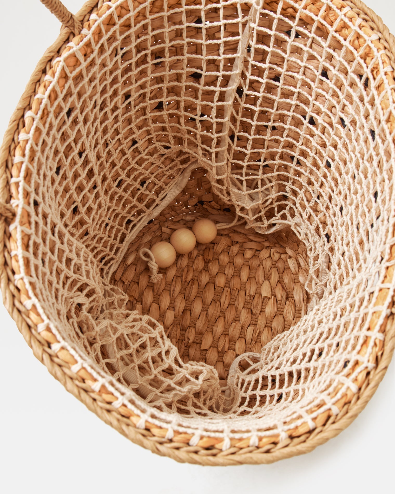 Top-down interior view of the Palma Nights Bag in natural-black showing the open-weave net lining and wooden bead detail at the base.