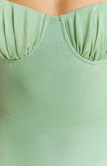 Close-up of the ruched sweetheart bust detail and sheer green mesh fabric of the midi dress