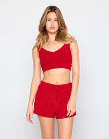 Woman wearing a cozy, red ribbed knit lounge set consisting of a cropped tank top and matching high-waisted drawstring shorts