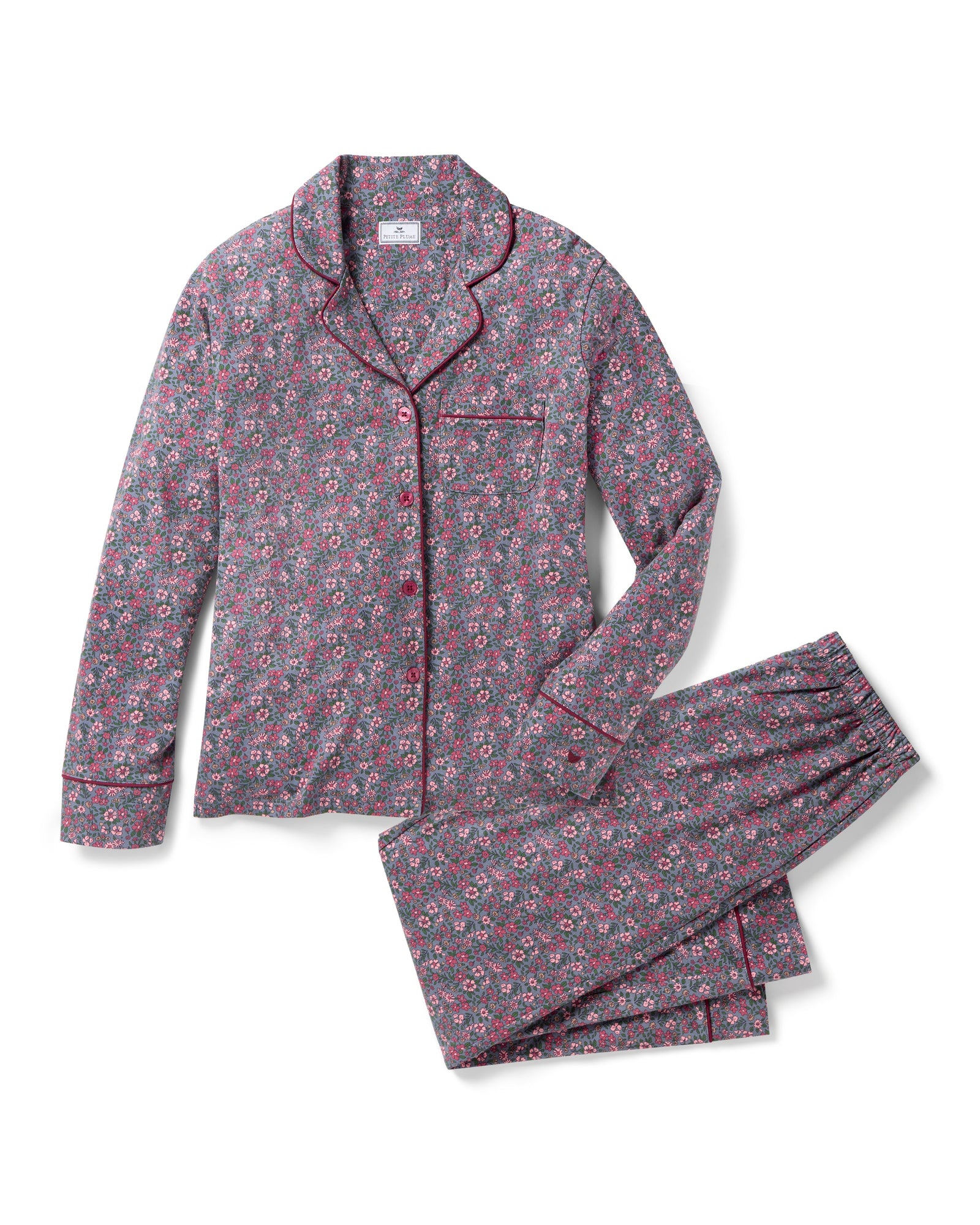 The Women's Pima Pajama Set in Fleurs de Saison features long sleeves and a small floral print in pink, white, and blue on gray. The set includes a button-up top with a chest pocket and matching pants.