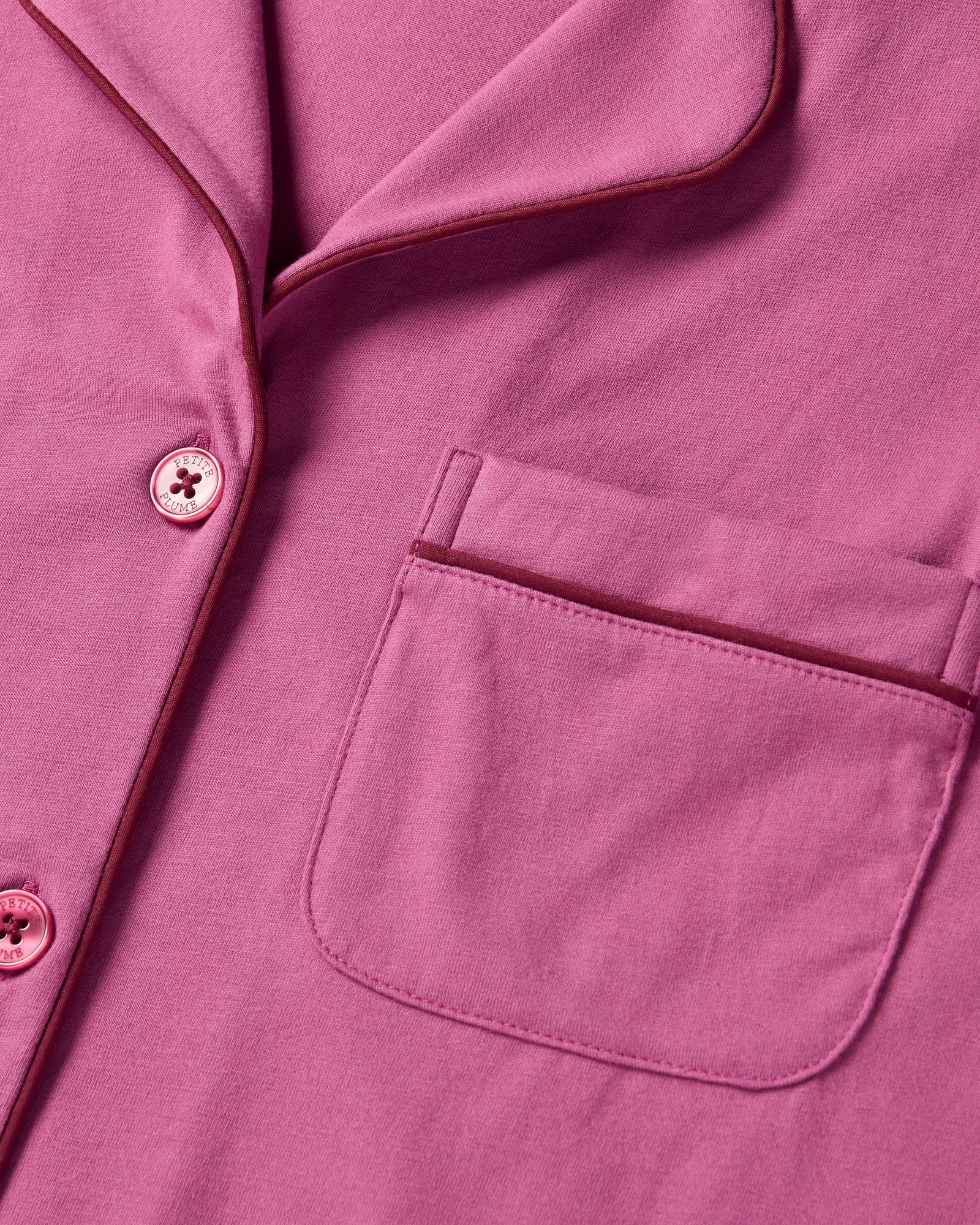 The Women's Pima Pajama Set in Rosewood, featuring a long-sleeve button-up top with a collar and chest pocket, and elastic-waist pants, is shown laid flat on a white background.