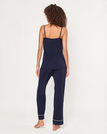The Women's Pima Sylvie Pajama Set in Navy includes a sleeveless V-neck camisole with thin straps and matching long pants, both featuring white trim. The set is displayed flat on a white background.