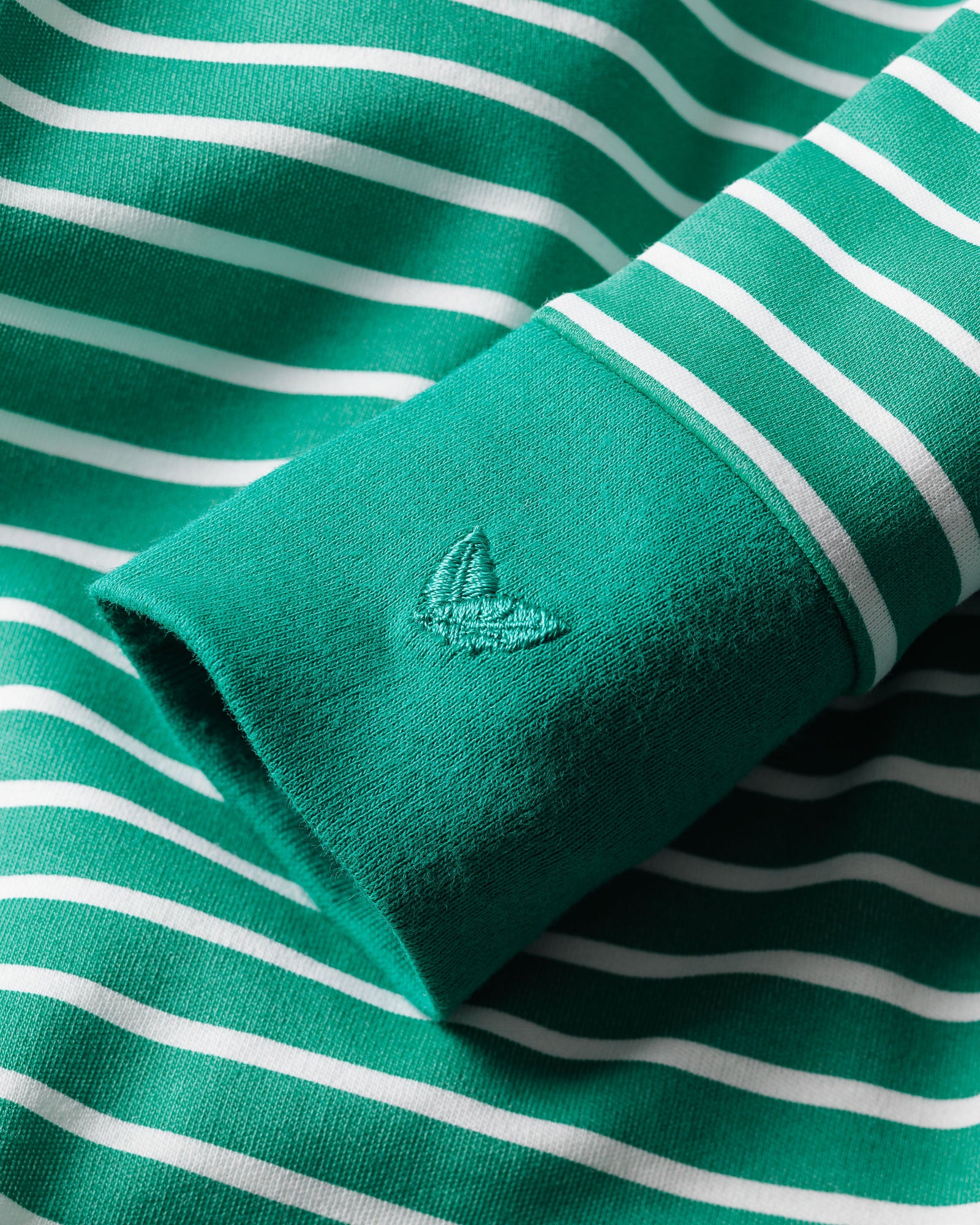 Close-up of a luxuriously crafted Babys Pima Romper in Green Stripe by Petite Plume, featuring a green and white stripe design with an embroidered tree on the sleeve, perfect for elegant daywear.