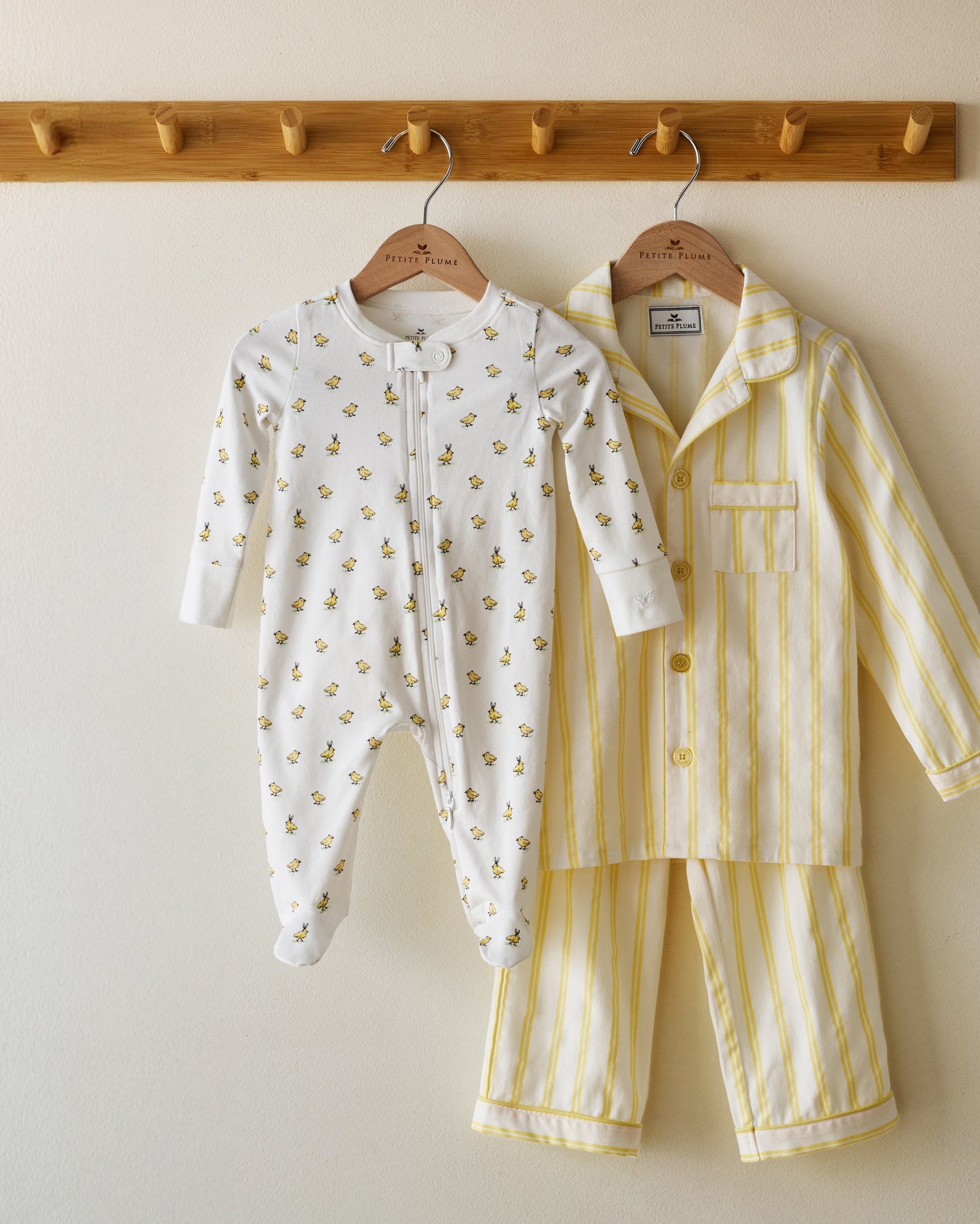 The Baby's Pima Romper in Tres Chick is a white, long-sleeve onesie with a yellow duckling print, footed bottoms, folded cuffs, and a zipper running from the collar to one leg.