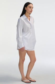 Woman wearing a white and pink stripe sheer shirt and shorts on a white background