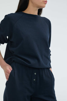 Person wearing a navy blue outfit with a plain background