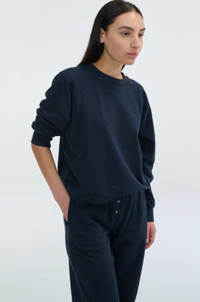 Person wearing a navy blue sweatshirt and pants on a white background