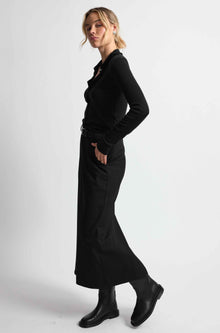 Woman wearing a black outfit on a light grey background