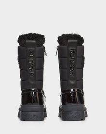 A pair of waterproof Rudsak LEX - 8222501 BLACK women’s boots with quilted sides, patent leather heels, and thick rugged soles, shown from behind against a white background.