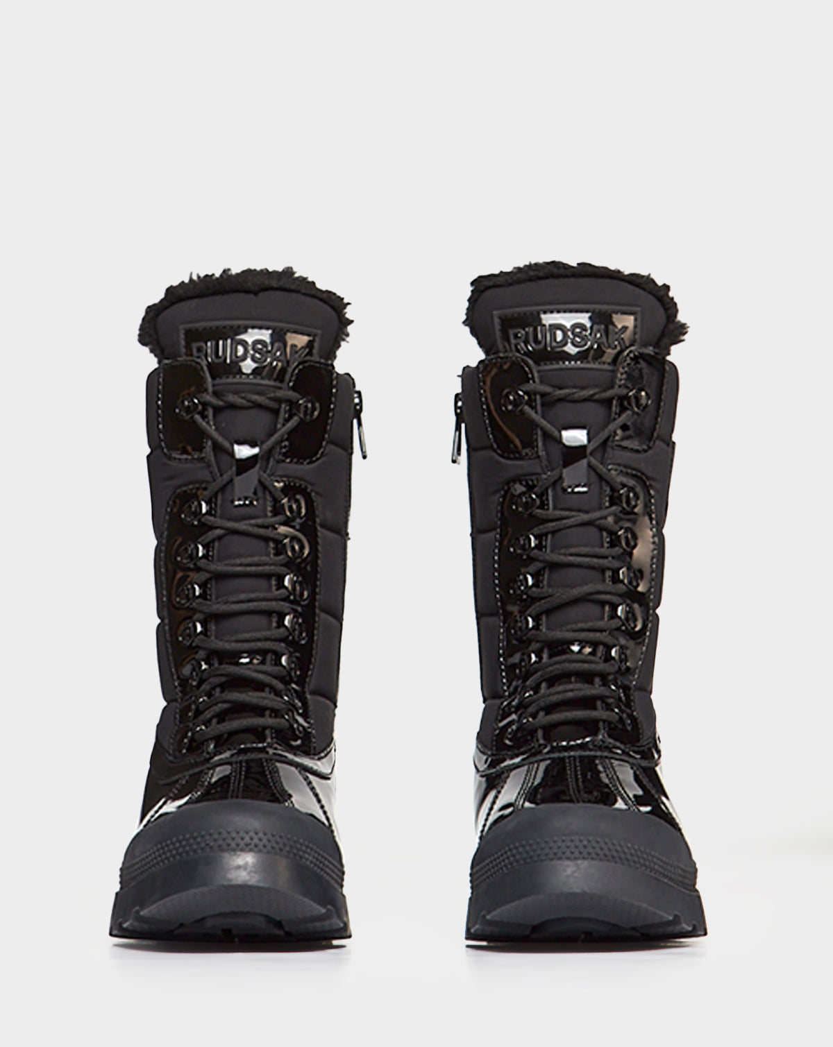 The Rudsak LEX - 8222501 BLACK boots feature shiny black leather, fur trim, front laces, and thick soles. Displayed facing forward on a white background, these waterproof winter boots are ideal for cold weather.