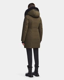 A person faces away, wearing a Rudsak MAIA M - 8123582 Army womens down parka with black fur trim, black pants, and black lace-up boots against a plain white background.