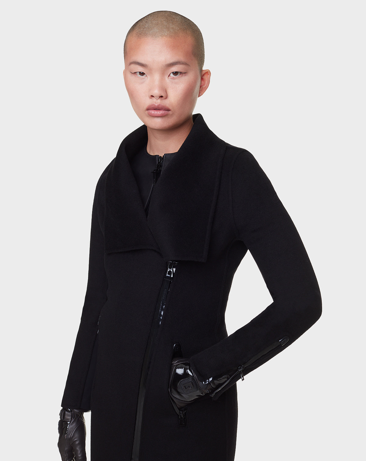 A person with short hair wears the RUDSAK CHAY - 8122506 BLACK double-faced wool coat with a wide collar and black gloves, standing against a plain white background.
