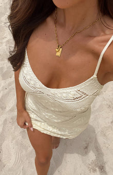 Close-up of the cream knit mini dress showing intricate open-knit patterns and a scoop neckline