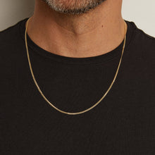 Model. Gold chain necklace worn by a person on a plain background