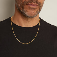Model. Man wearing a gold chain necklace against a neutral background