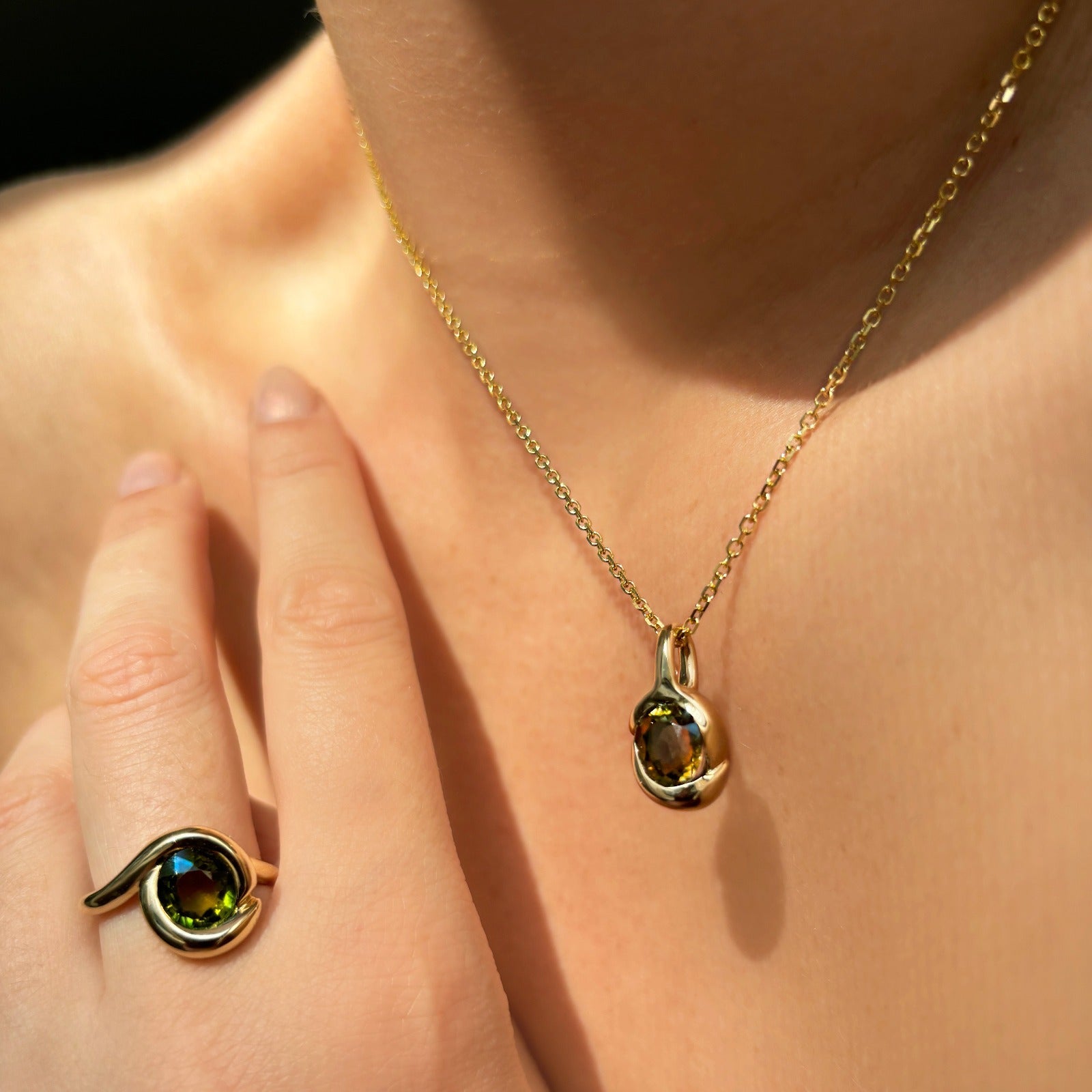 Molten knot charm with gemstone. Styled on a neck hanging from the diamond cut cable chain necklace.