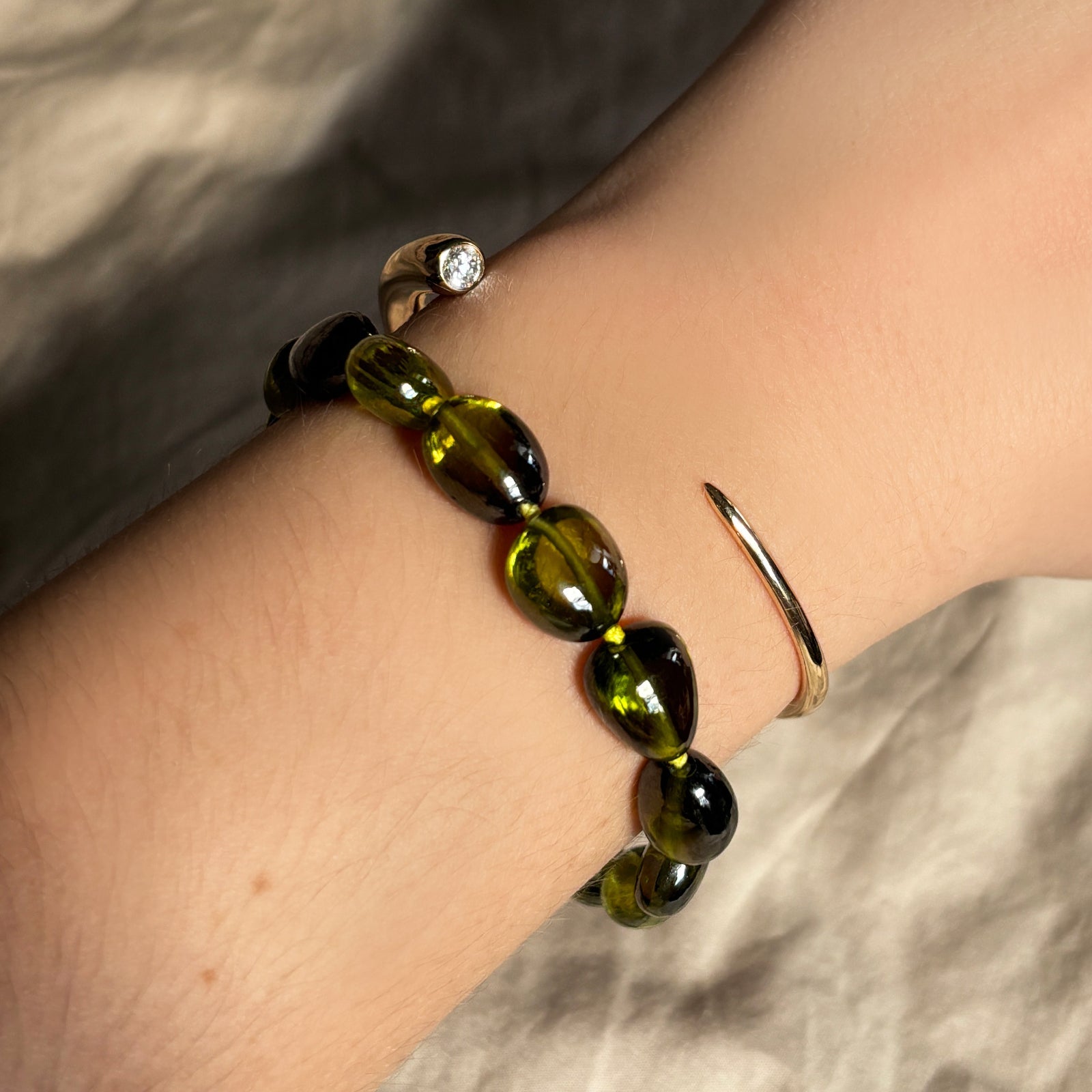 green nugget zircon bracelet with neon lime knots and quill cuff in yellow gold with a diamond stacked on the wrist.