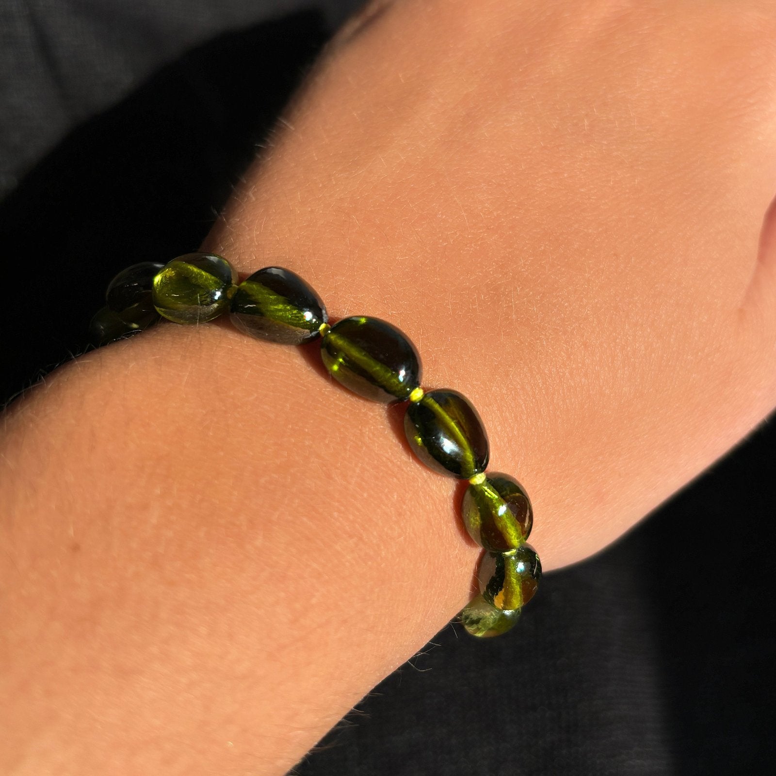Shimmering beaded Green Zircon nugget bracelet with shades of green, yellow, and olive on a gold lobster clasp, l on a wrist.