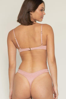 Pink sparkle thong bikini bottom with bound sides shown on model from back view.